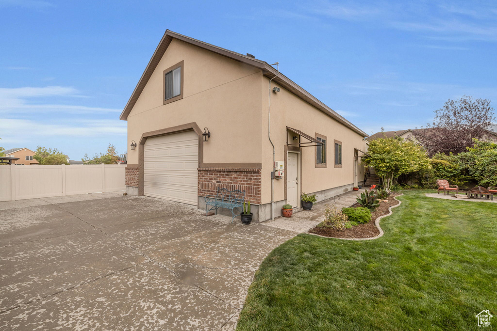 View of side of home featuring a yard and a garage