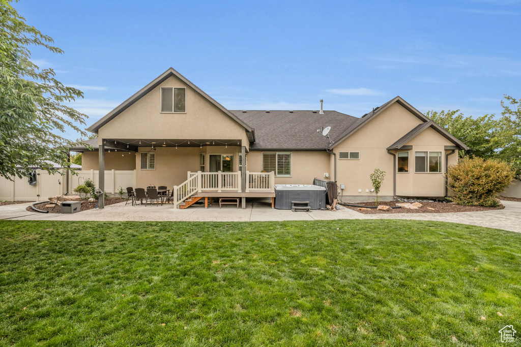 Back of property featuring a hot tub, a yard, a patio area, and an outdoor fire pit