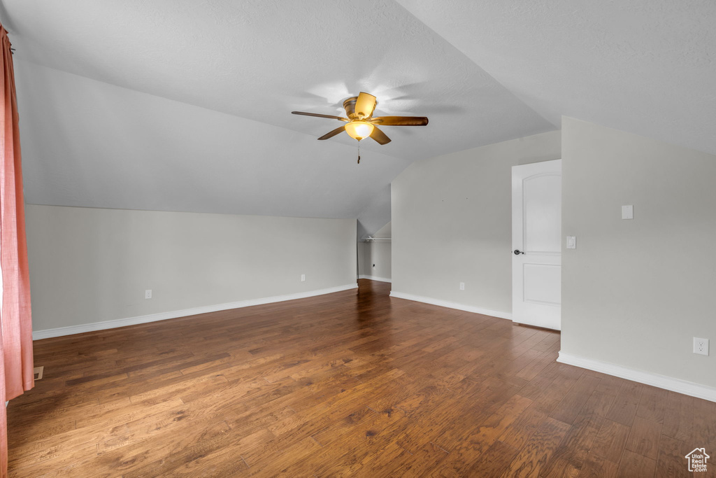 Bonus room featuring ceiling fan, vaulted ceiling, a textured ceiling, and dark wood-type flooring