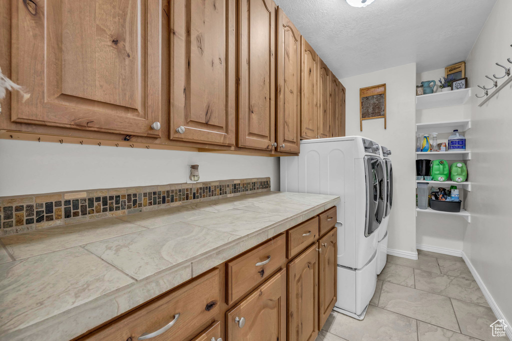 Washroom with cabinets, a textured ceiling, and separate washer and dryer