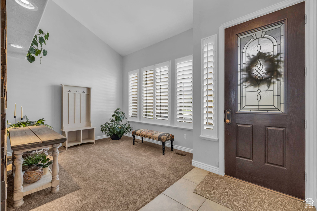 Carpeted entryway featuring lofted ceiling