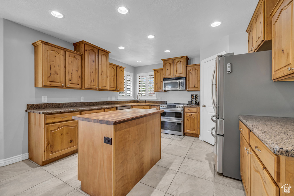 Kitchen featuring appliances with stainless steel finishes, a kitchen island, and sink