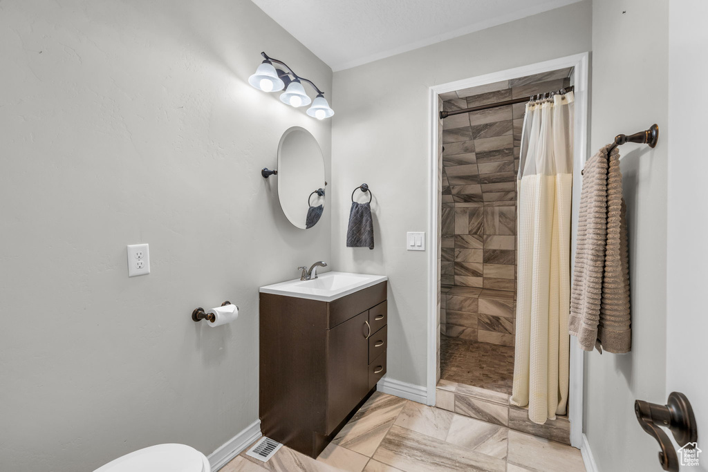 Bathroom featuring toilet, vanity, curtained shower, and tile patterned flooring