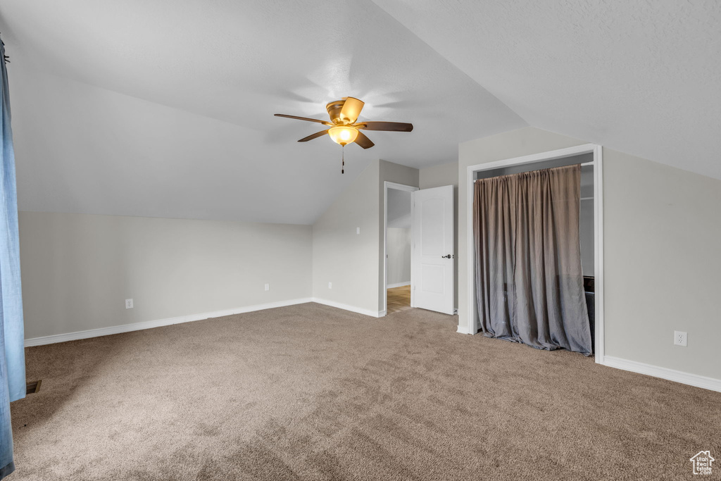 Additional living space with lofted ceiling, carpet flooring, and ceiling fan