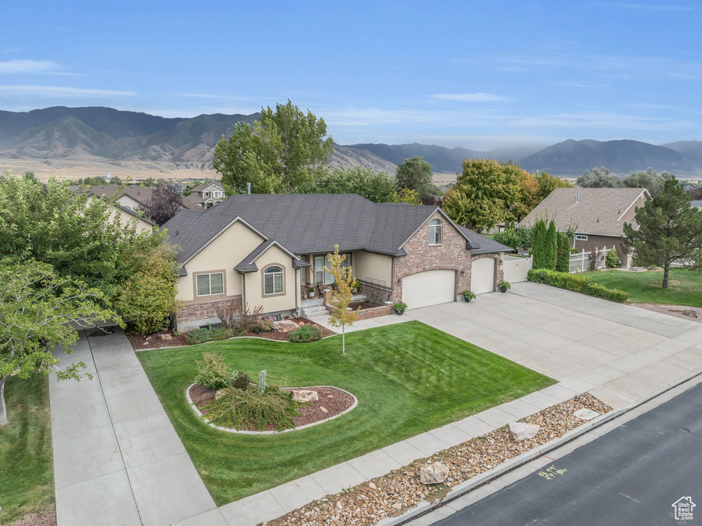 View of front facade with a mountain view, a garage, and a front lawn