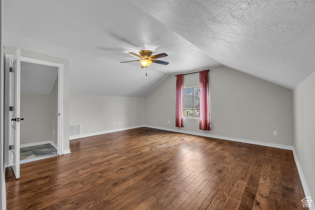 Additional living space featuring a textured ceiling, lofted ceiling, ceiling fan, and dark hardwood / wood-style flooring