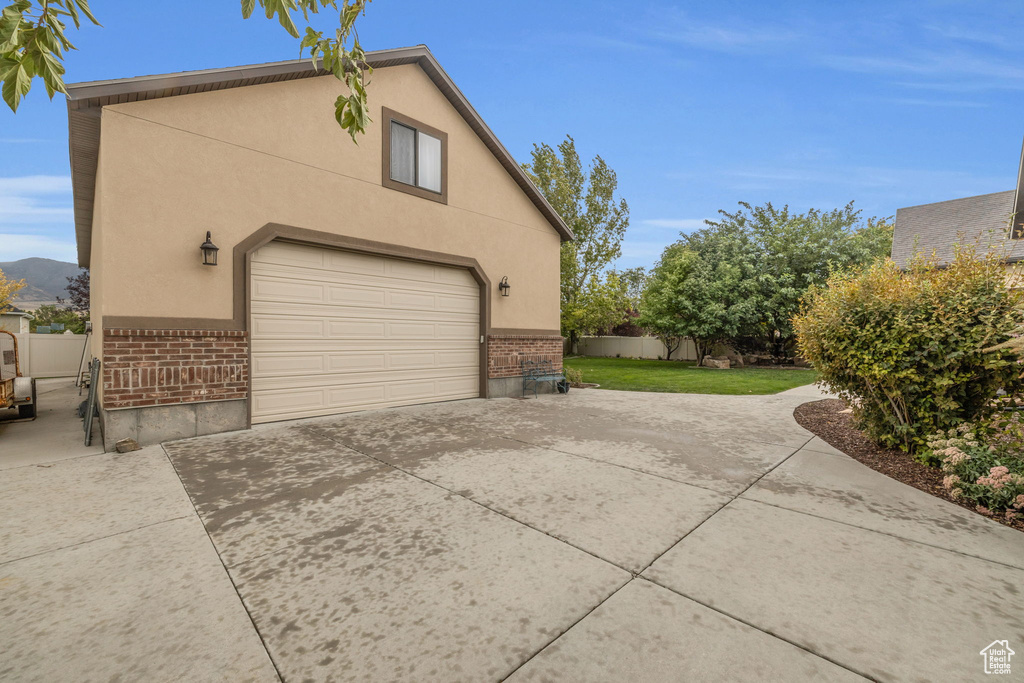 View of side of property with a mountain view, a garage, and a yard