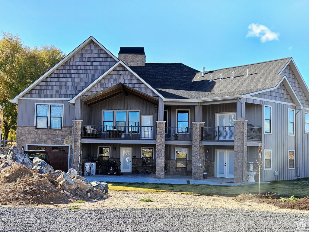 Rear view of property with a balcony, a garage, and a patio area