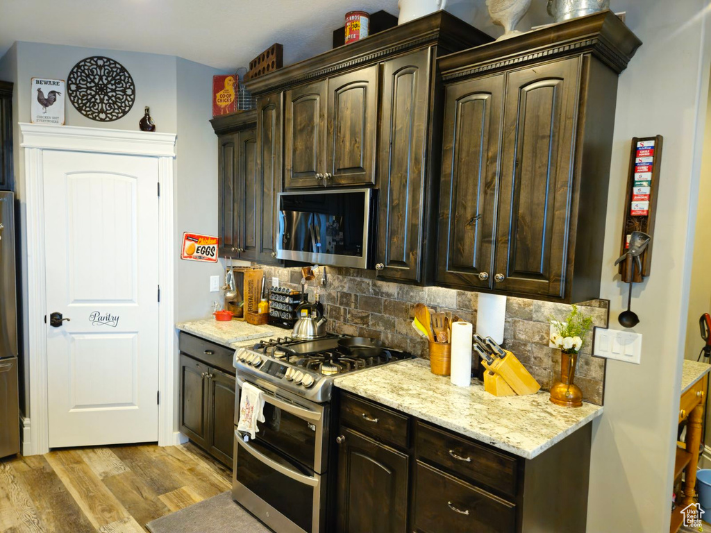 Kitchen featuring dark brown cabinets, light wood-type flooring, and appliances with stainless steel finishes