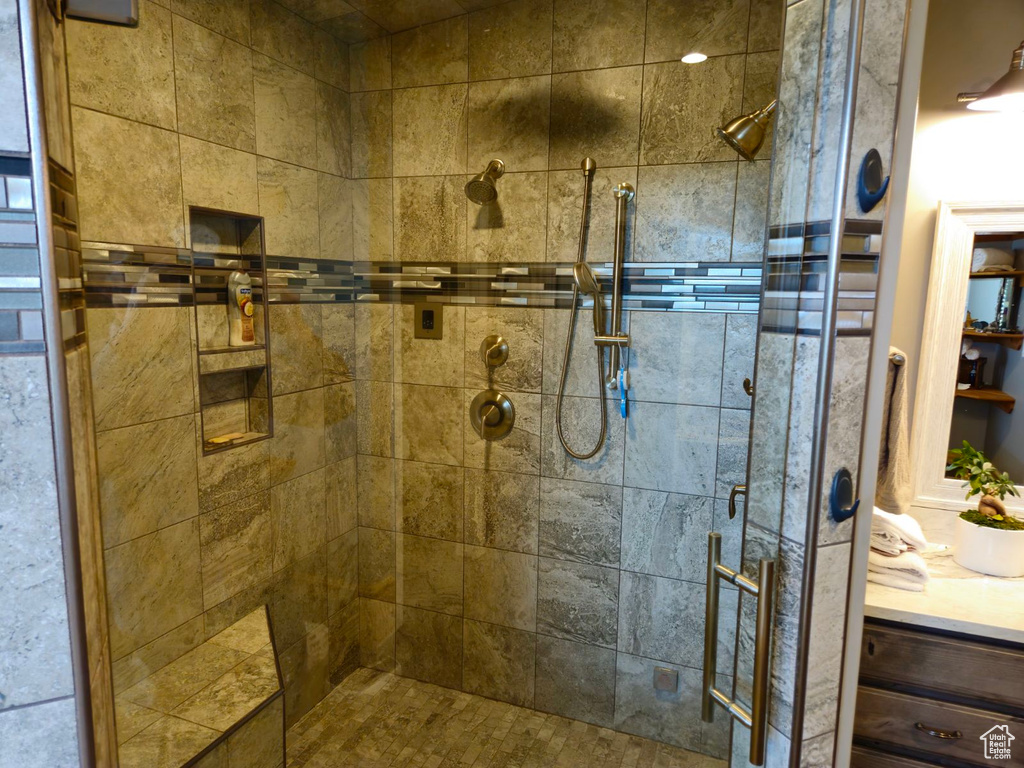 Bathroom featuring a shower with shower door and vanity