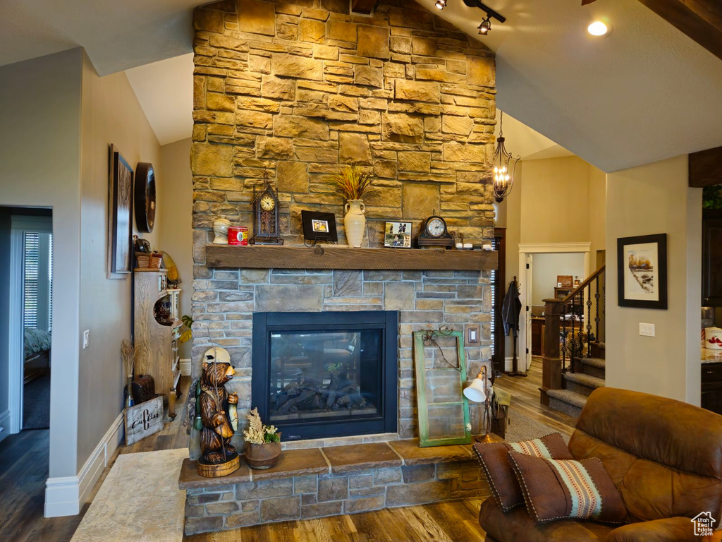 Living room with a stone fireplace, lofted ceiling, and dark wood-type flooring