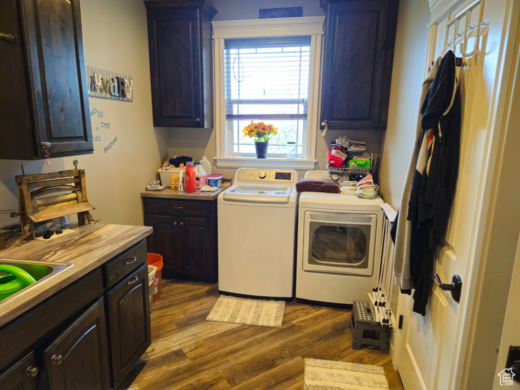 Washroom featuring wood-type flooring, washer and dryer, and cabinets