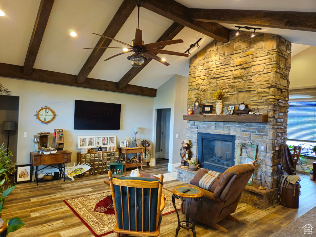 Living room featuring high vaulted ceiling, a fireplace, beam ceiling, ceiling fan, and light hardwood / wood-style flooring