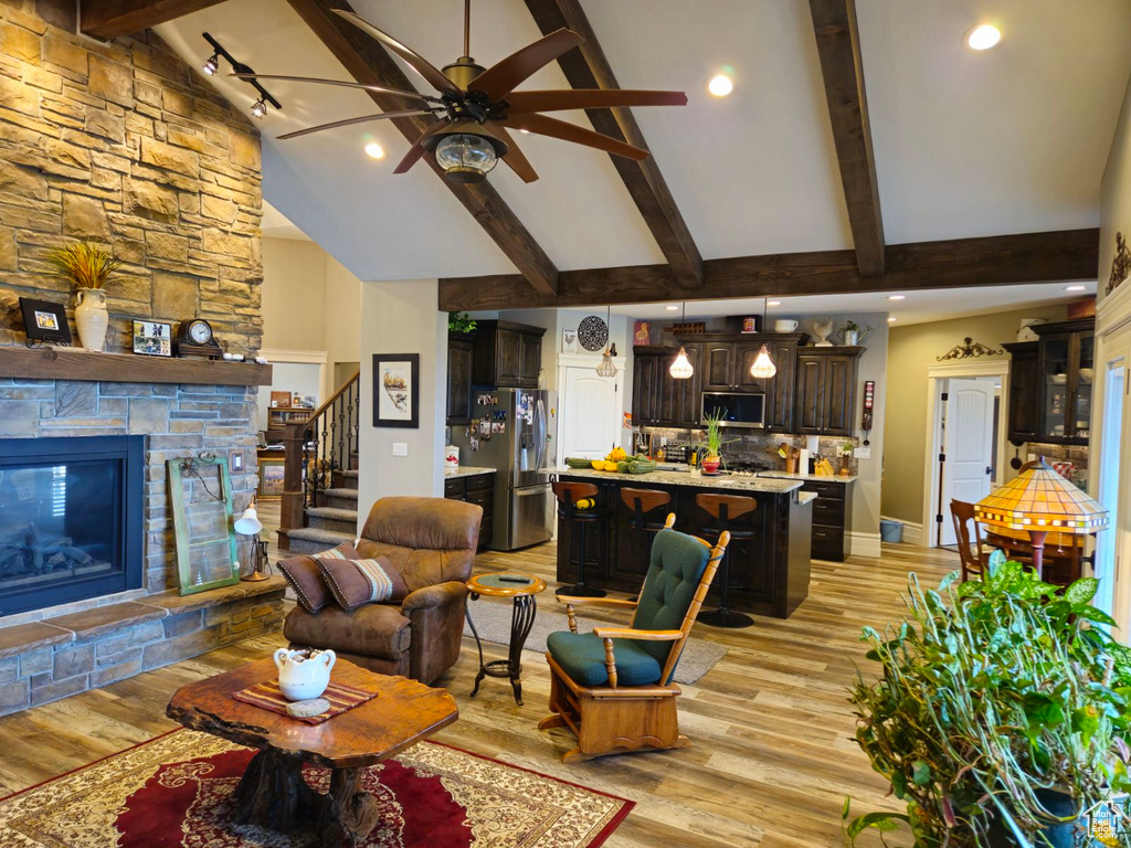 Living room with high vaulted ceiling, a fireplace, beamed ceiling, light wood-type flooring, and ceiling fan