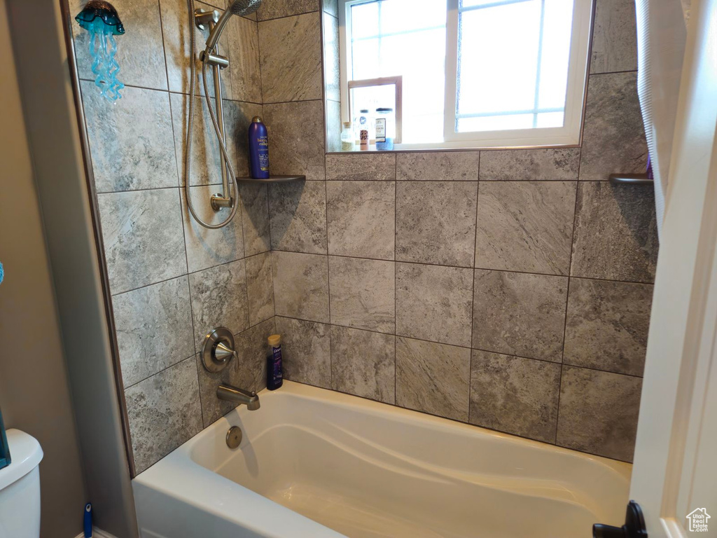 Bathroom featuring tiled shower / bath and toilet