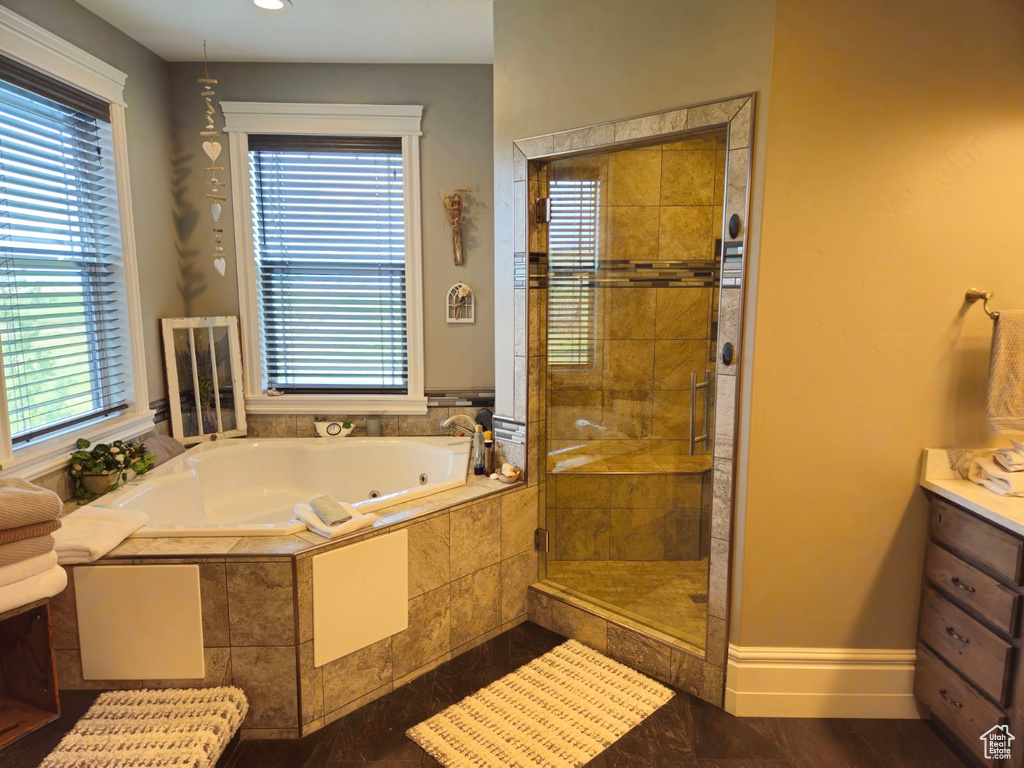 Bathroom featuring independent shower and bath, vanity, and a wealth of natural light