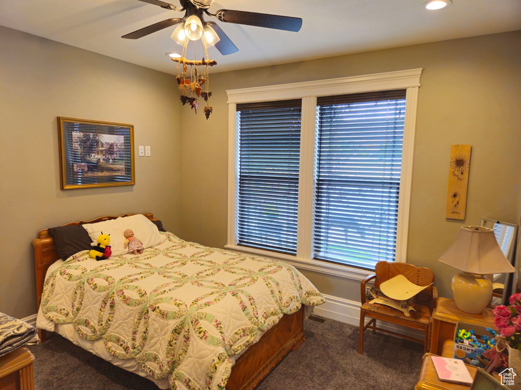 Bedroom featuring ceiling fan, dark carpet, and multiple windows