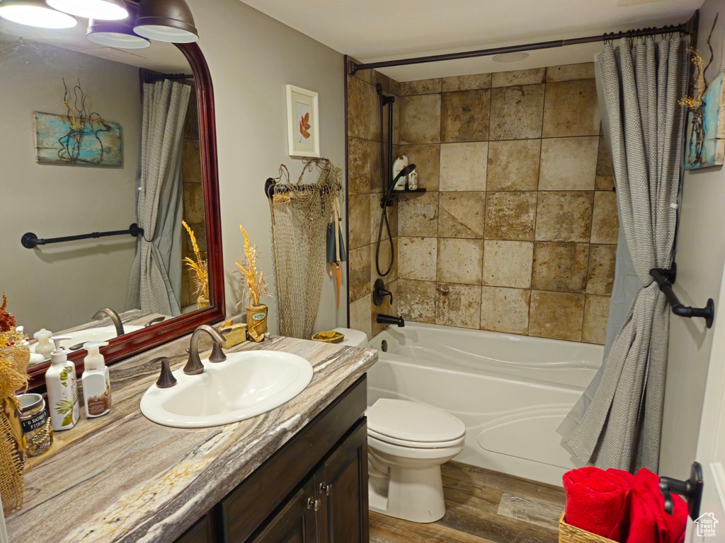 Full bathroom with shower / bath combination with curtain, vanity, hardwood / wood-style floors, and toilet