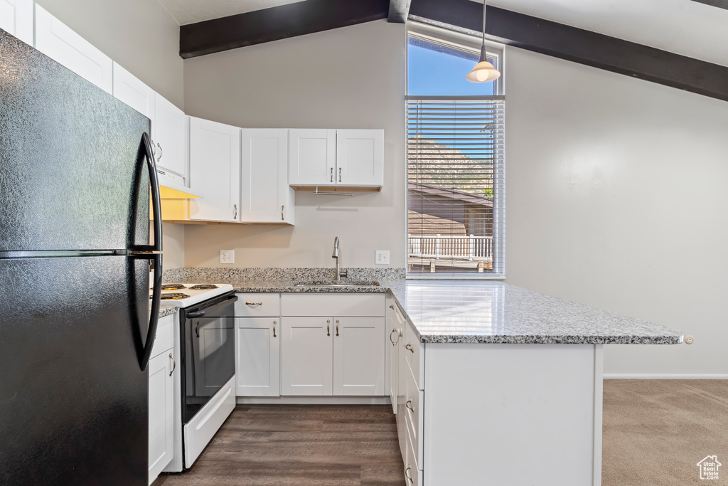 Kitchen with white electric stove, sink, black refrigerator, and white cabinetry