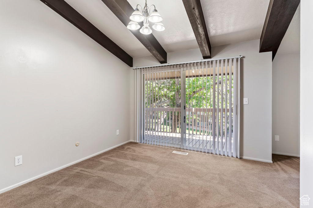 Spare room with light carpet, vaulted ceiling with beams, and a chandelier