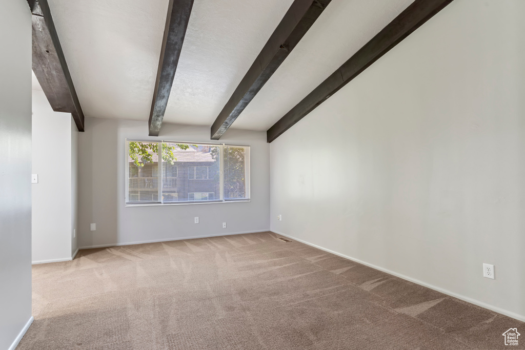 Carpeted empty room with beam ceiling