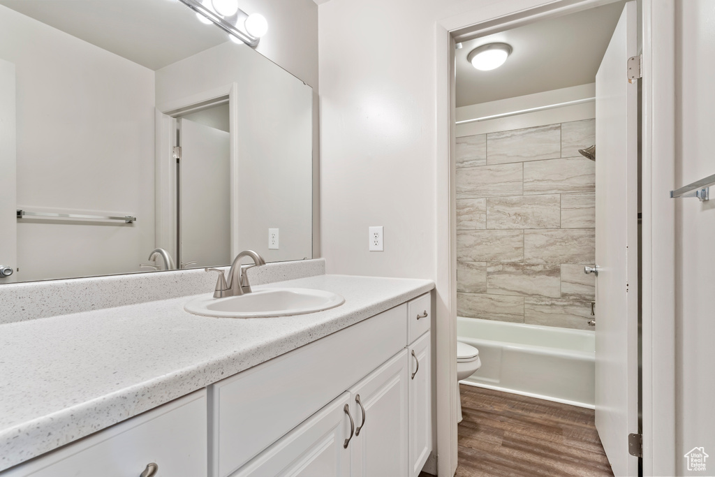 Full bathroom with hardwood / wood-style floors, vanity, toilet, and tiled shower / bath combo