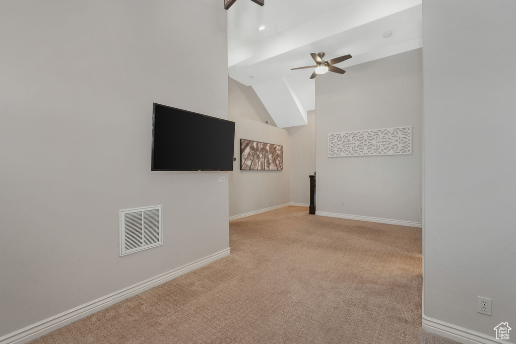 Unfurnished living room with ceiling fan, light colored carpet, and vaulted ceiling