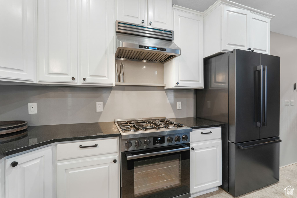 Kitchen with white cabinets, appliances with stainless steel finishes, and ventilation hood