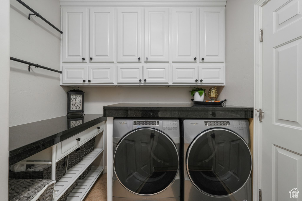 Laundry room featuring washer and clothes dryer and cabinets