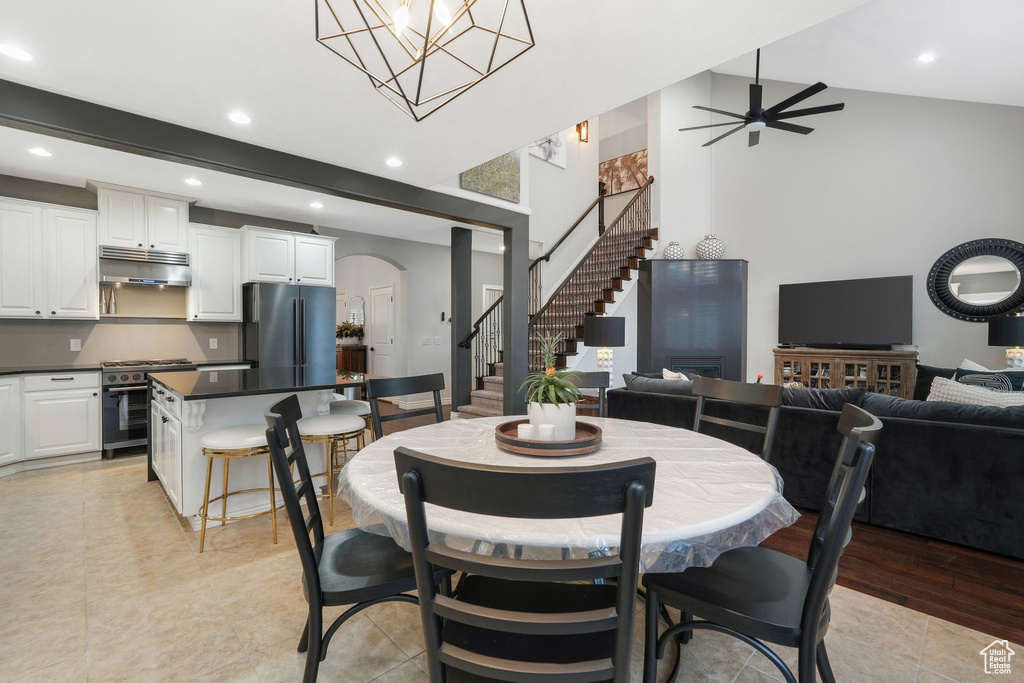 Dining room with light hardwood / wood-style floors, ceiling fan with notable chandelier, and lofted ceiling