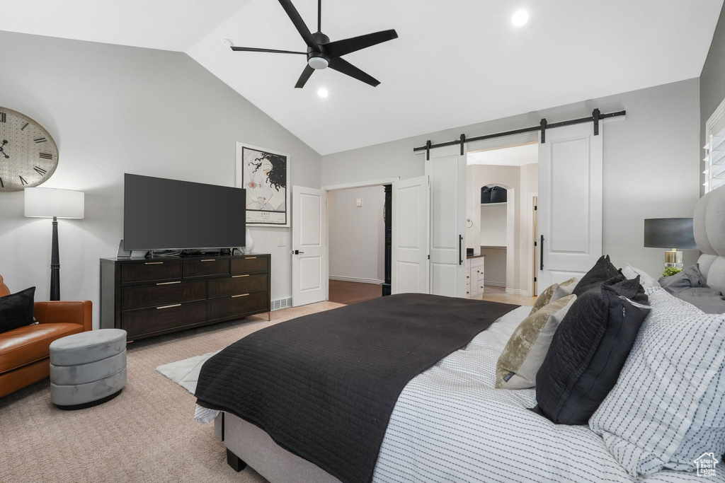 Carpeted bedroom featuring ceiling fan, ensuite bathroom, lofted ceiling, and a barn door