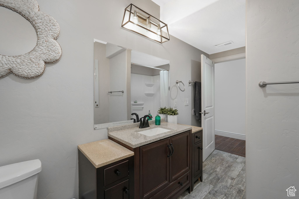 Bathroom with vanity, hardwood / wood-style floors, and toilet