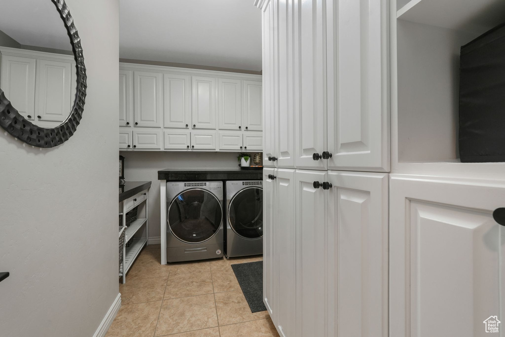 Washroom with washer and clothes dryer, cabinets, and light tile patterned floors