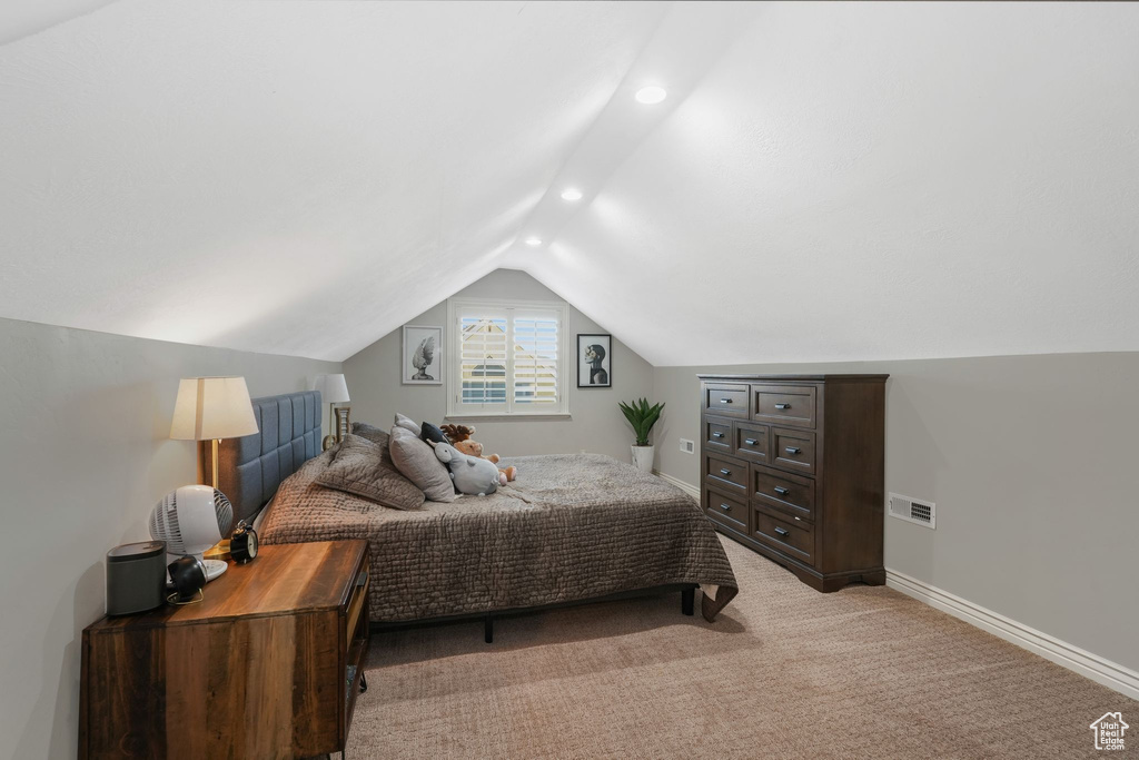 Bedroom with vaulted ceiling and light colored carpet