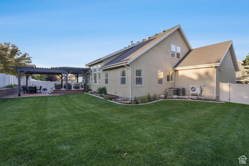 Rear view of property with a pergola, ac unit, a patio, and a yard