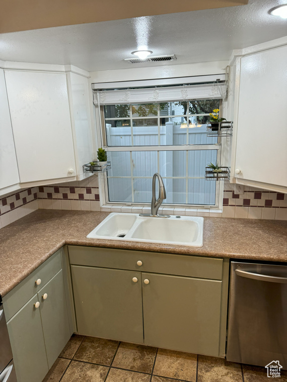 Kitchen featuring white cabinets, dishwasher, backsplash, and sink