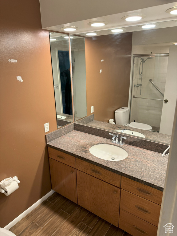 Bathroom featuring a shower with shower door, vanity, and toilet