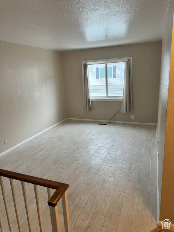 Unfurnished room featuring light wood-type flooring and a textured ceiling