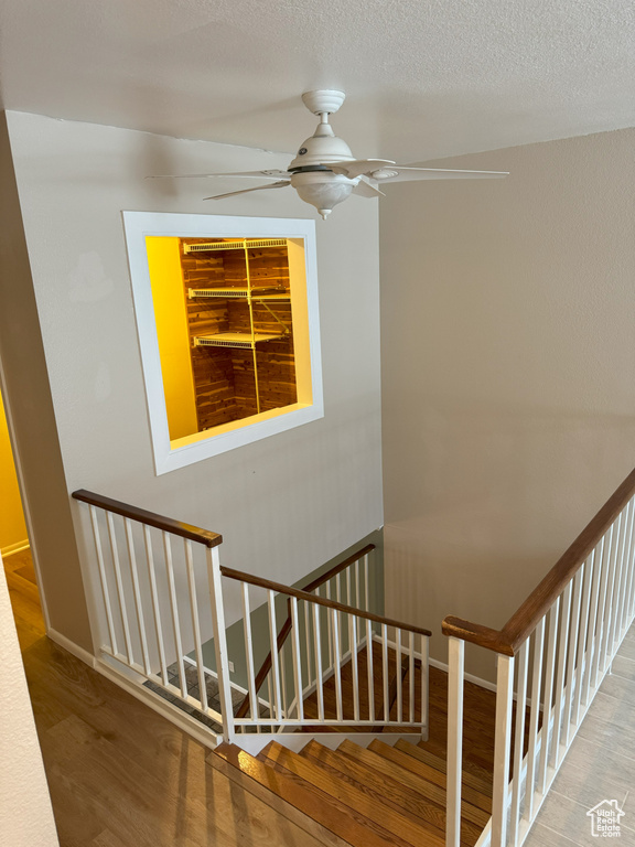 Stairs featuring a textured ceiling and hardwood / wood-style floors