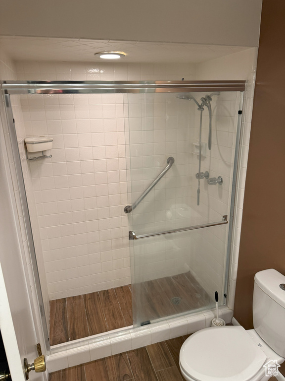 Bathroom featuring hardwood / wood-style floors, toilet, and a shower with shower door