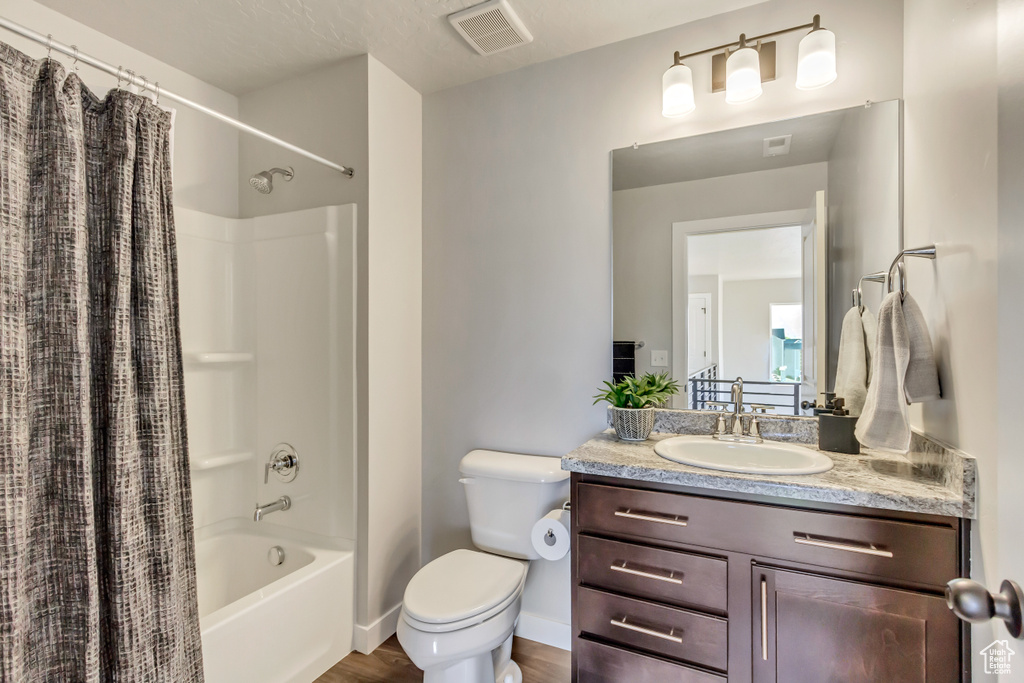 Full bathroom with vanity, toilet, hardwood / wood-style flooring, and shower / bath combo with shower curtain