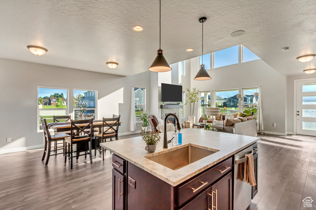 Kitchen featuring an island with sink, hanging light fixtures, sink, and hardwood / wood-style floors