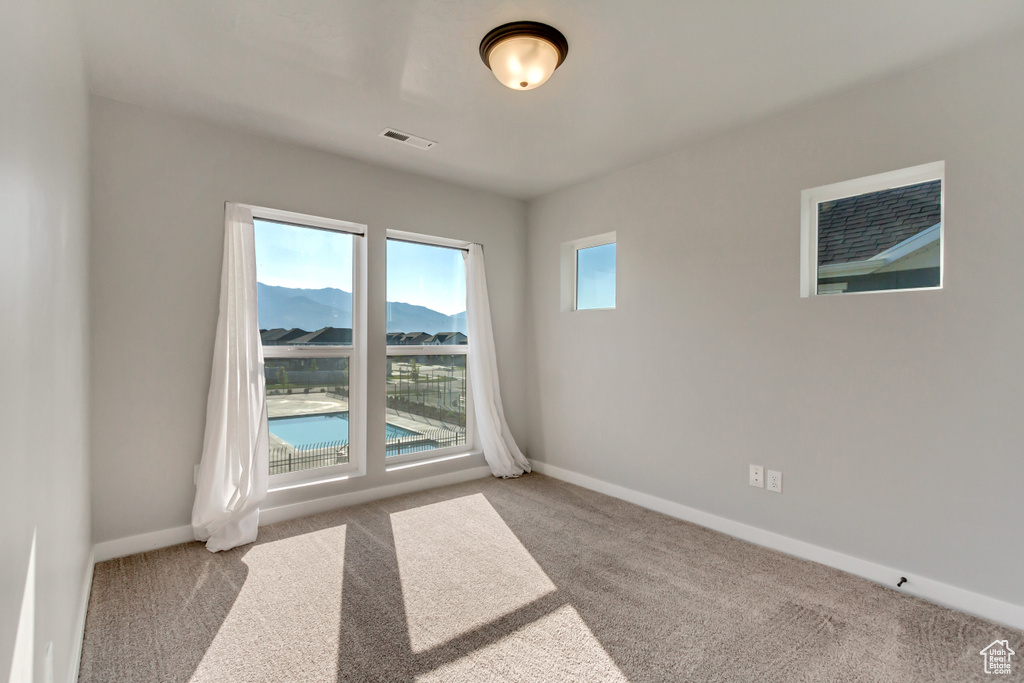 Unfurnished room featuring a mountain view and light carpet