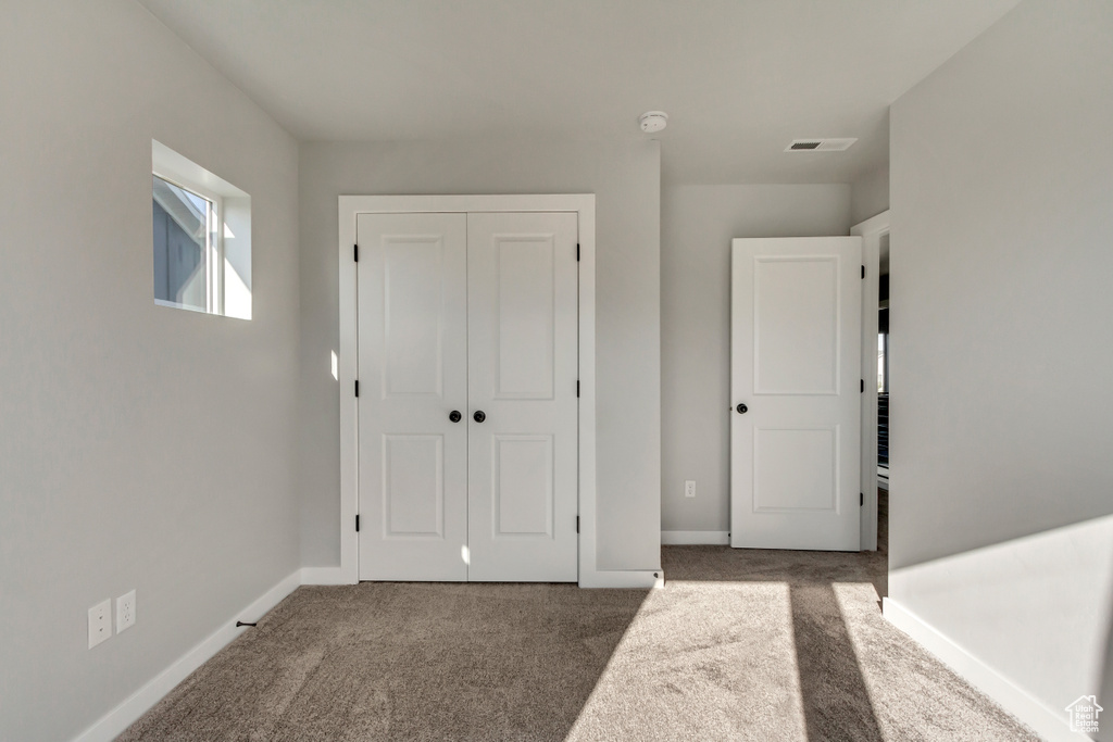 Unfurnished bedroom featuring dark colored carpet and a closet