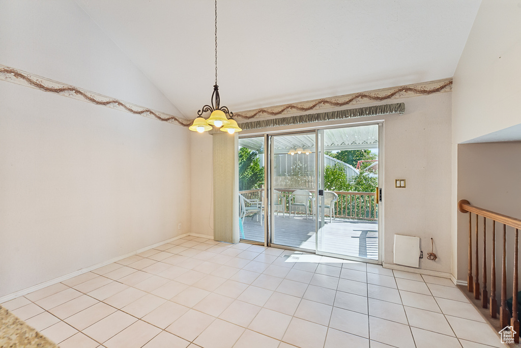 Spare room with high vaulted ceiling, a chandelier, and light tile patterned floors