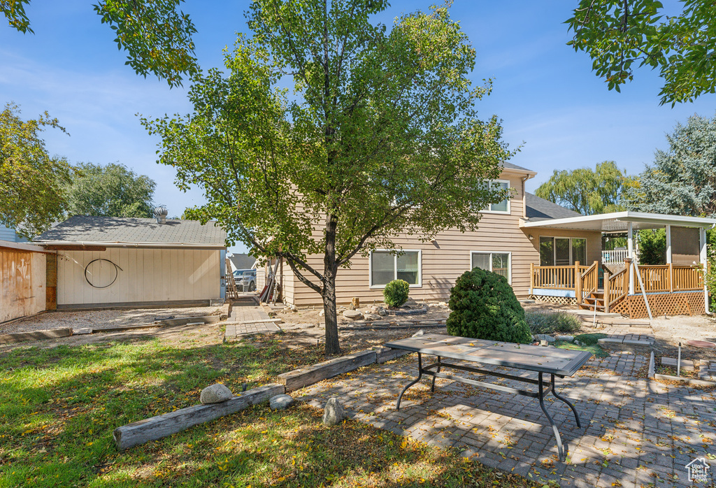 Rear view of property featuring a wooden deck and a patio