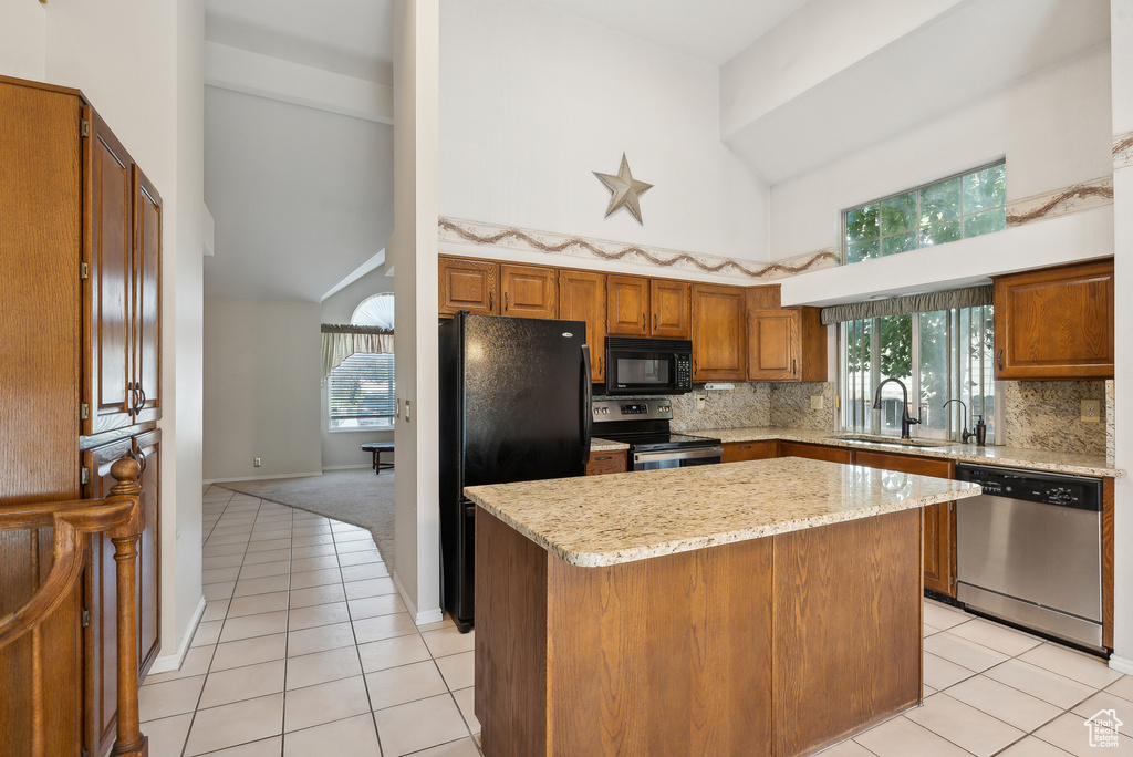 Kitchen featuring a center island, light tile patterned floors, high vaulted ceiling, and black appliances