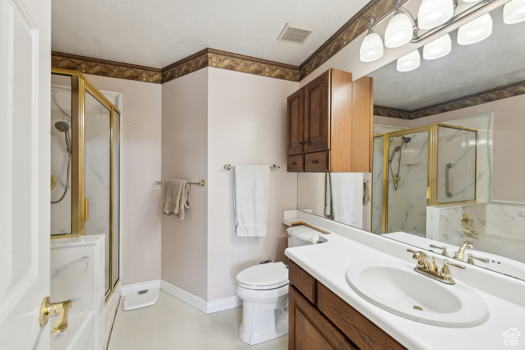 Bathroom featuring vanity, a textured ceiling, toilet, and an enclosed shower