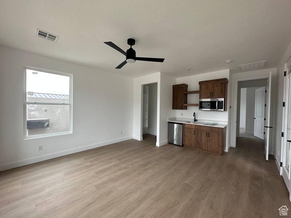 Kitchen featuring stainless steel appliances, sink, a textured ceiling, light hardwood / wood-style floors, and ceiling fan