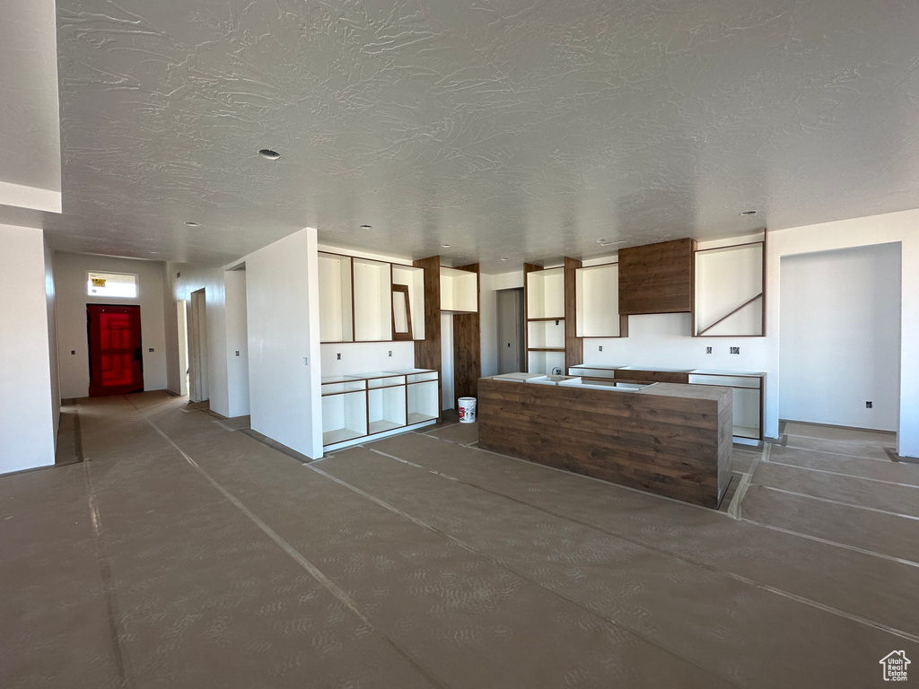 Kitchen with concrete flooring, a textured ceiling, and a center island